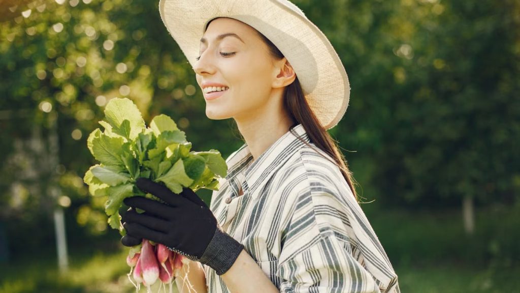 Happy woman enjoying a fresh harvest of radishes in a sunny garden.