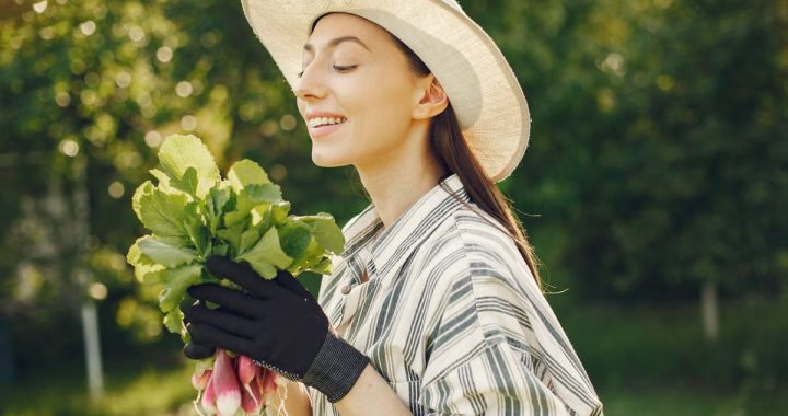 Happy woman enjoying a fresh harvest of radishes in a sunny garden.