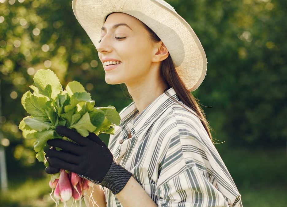 Happy woman enjoying a fresh harvest of radishes in a sunny garden.