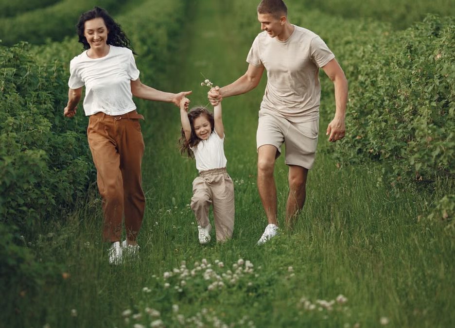 Joyful family enjoying a fun day outdoors in a green field, epitomizing togetherness and happiness.